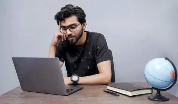 a student thinking while looking at laptop